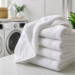 Fresh white bath towels folded on a countertop in a bright laundry room